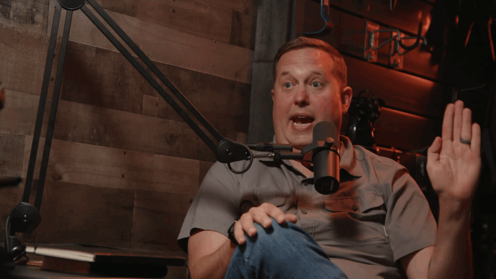 Rev. Chip Bennett holds up one hand while speaking into a microphone.